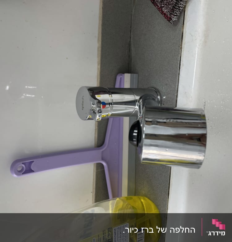 ברז כרום עם ידית סגולה ליד כיור